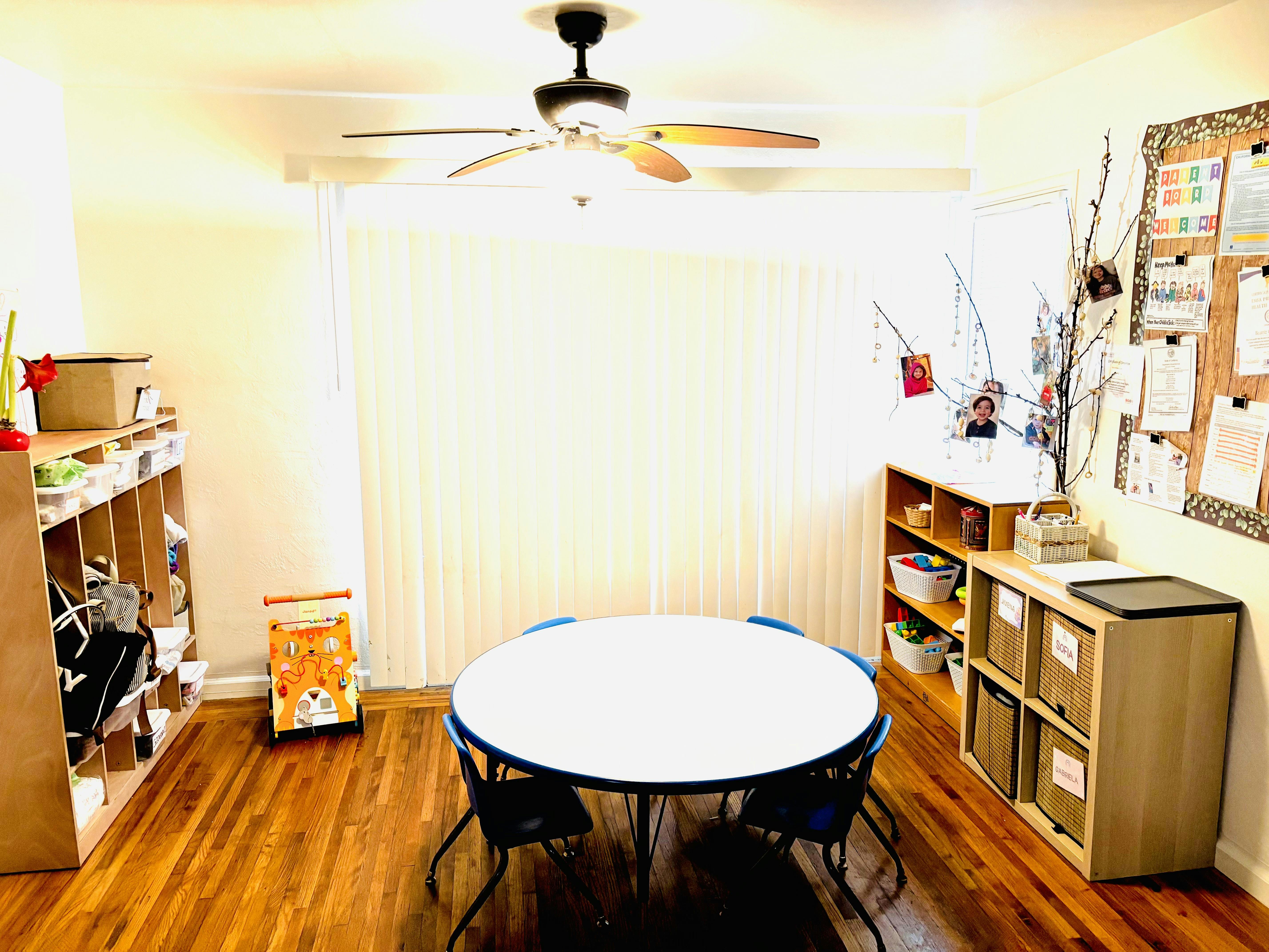 Classroom with a round table and chairs, storage shelves, and a bulletin board