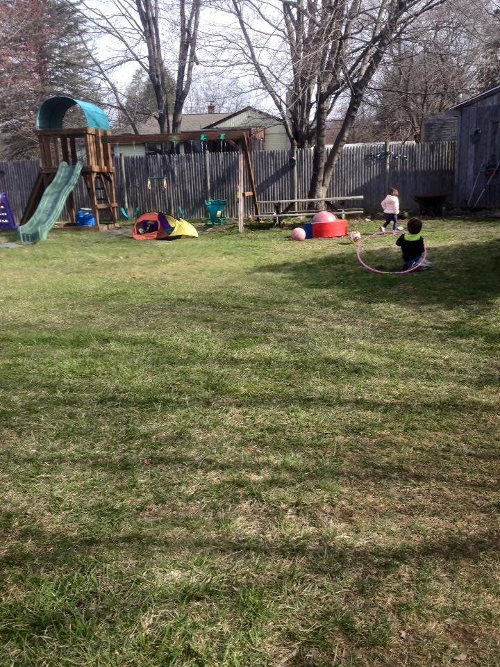 Children playing in a backyard with a playset