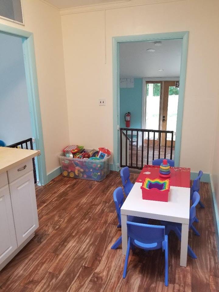 Playroom with small table and chairs, toy bin, and safety gate