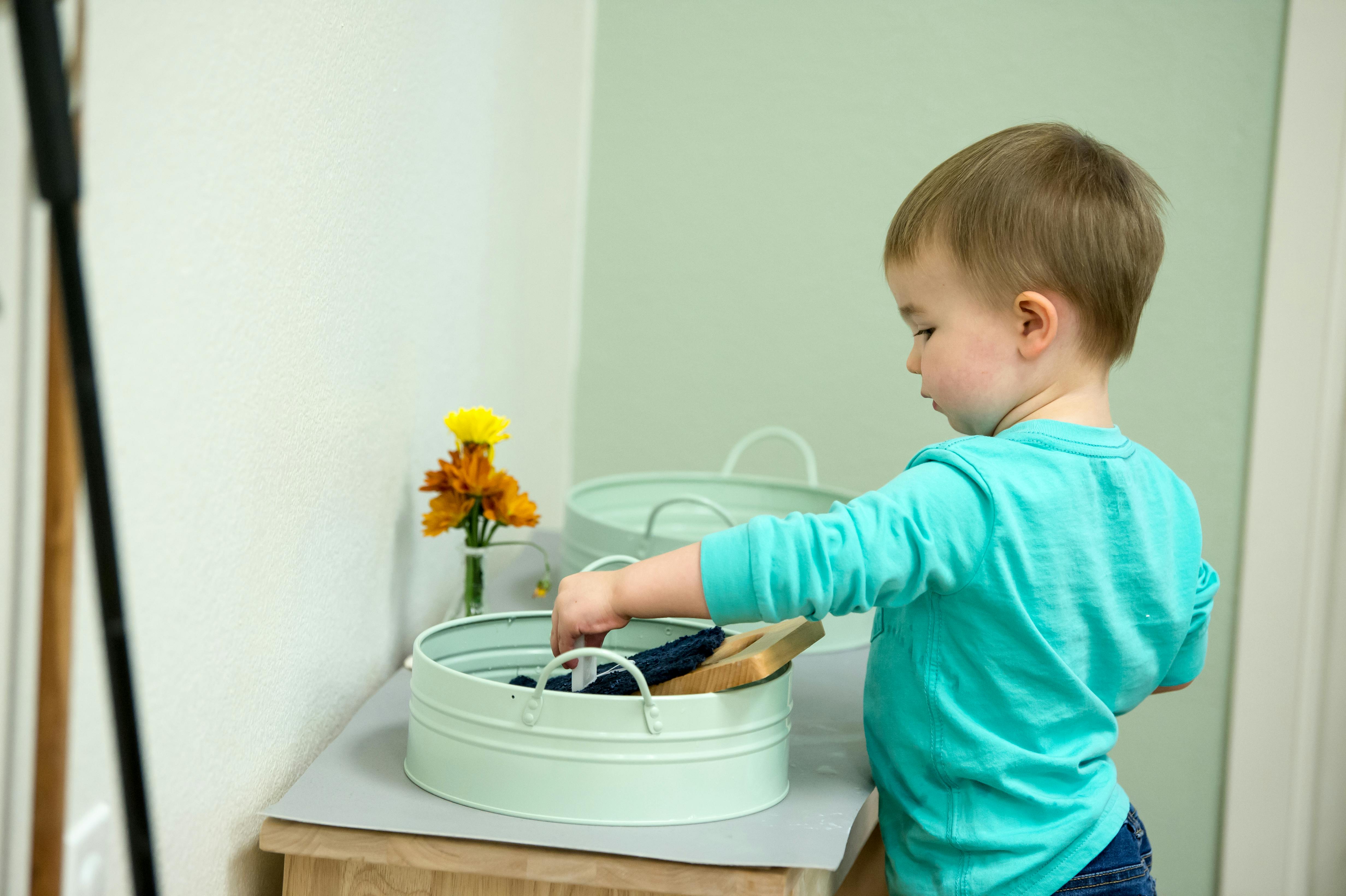 Child reaching into a light green metal bin