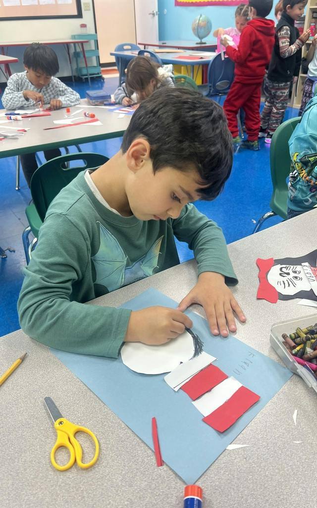 Child drawing on paper at a desk in a classroom