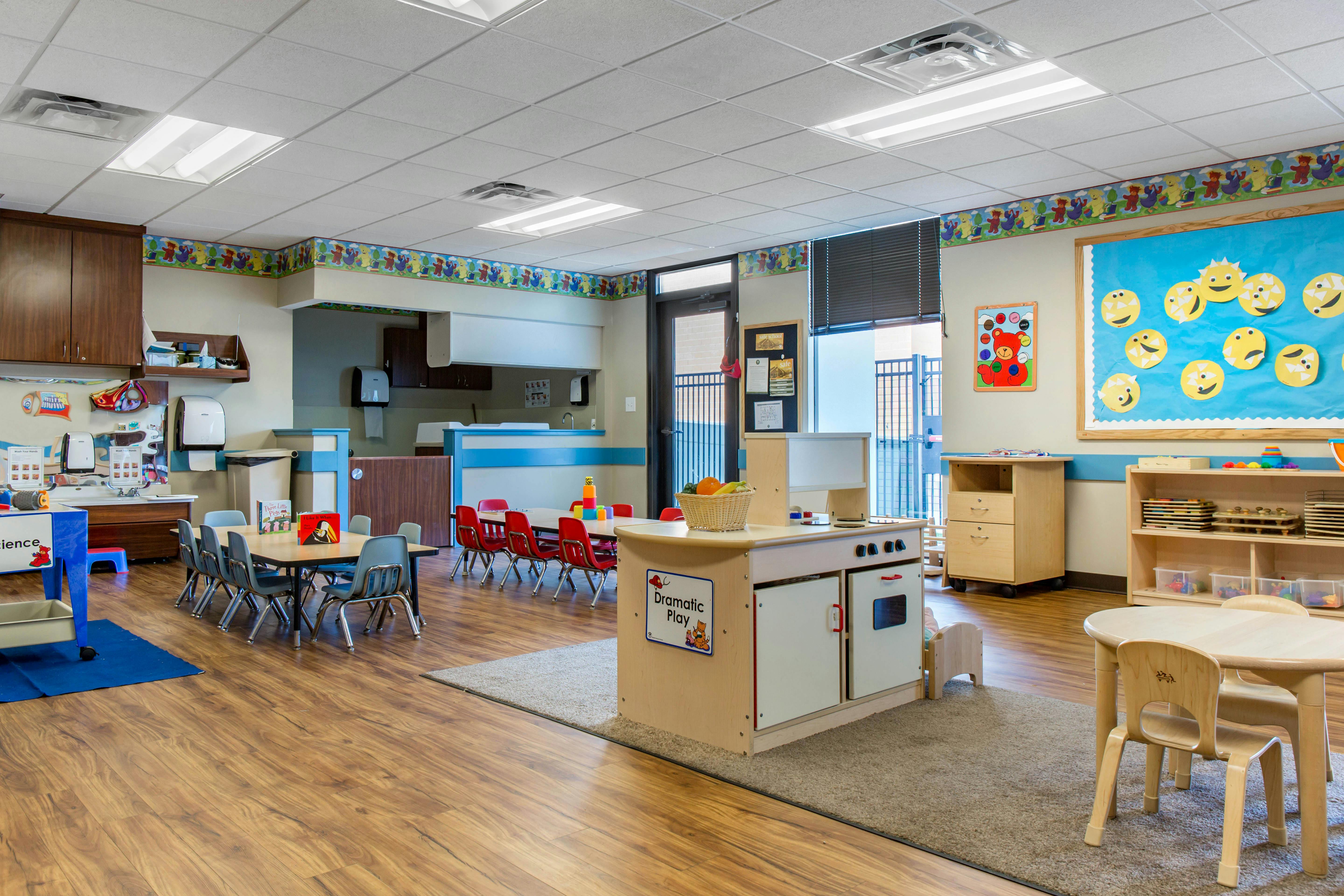 Classroom with tables and chairs, a play kitchen, and colorful decorations