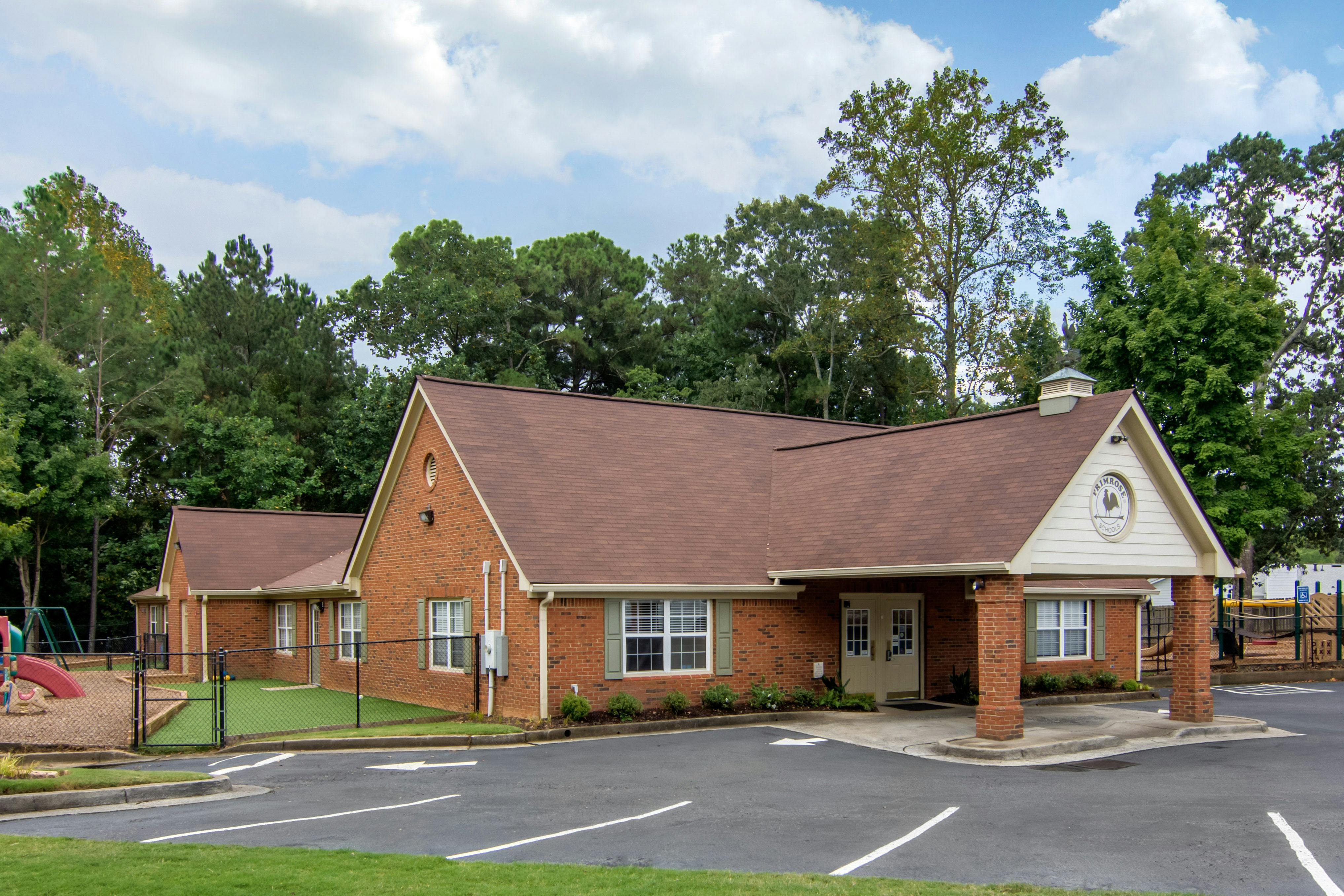Brick building with a brown roof and a playground area, next to a parking lot