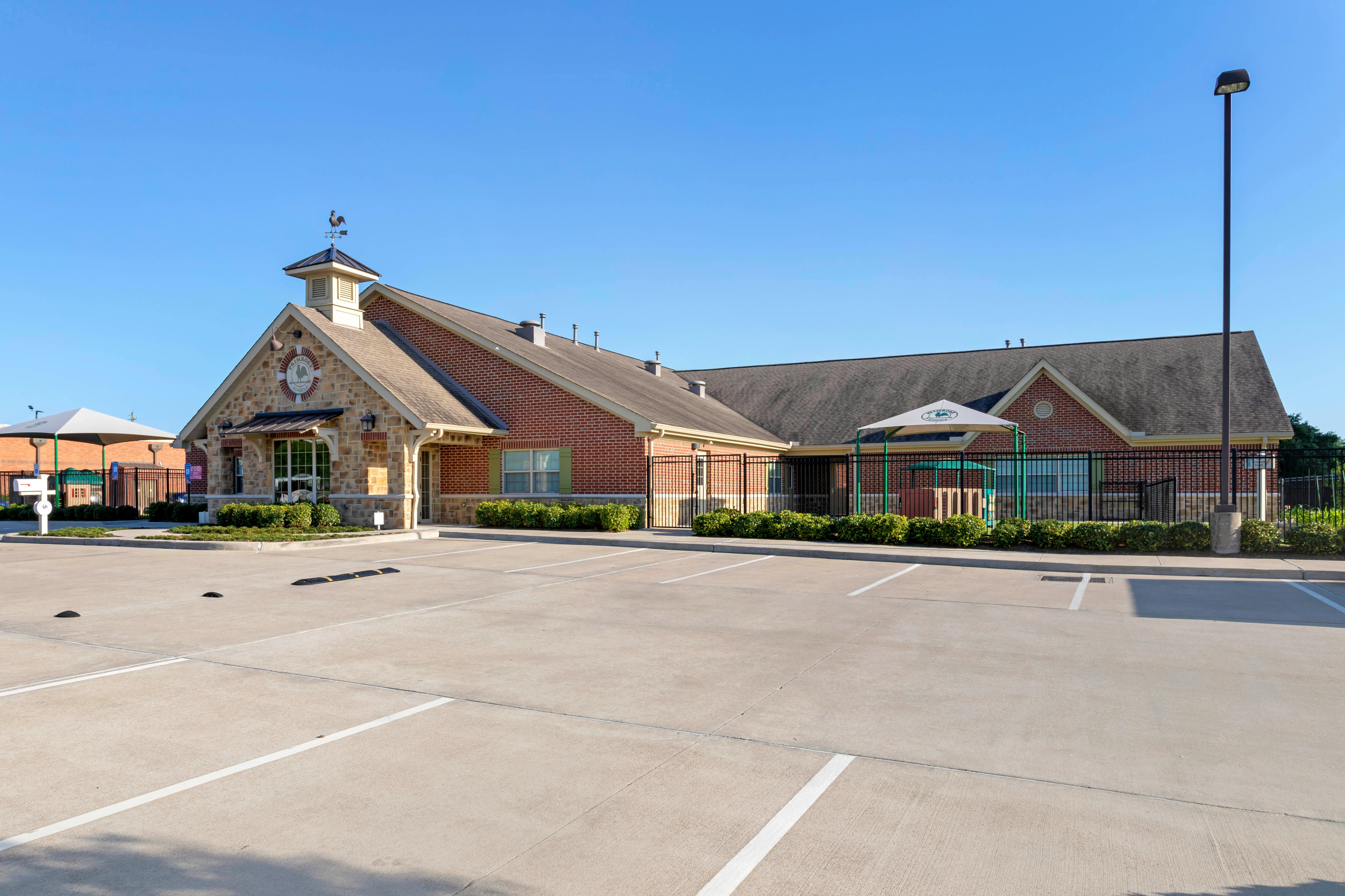 Brick and stone school building with a parking lot and playground area