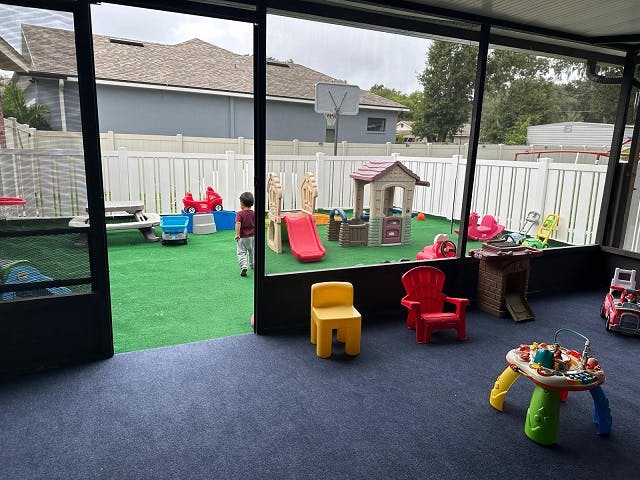 Child walking in an outdoor play area with slides and playhouses