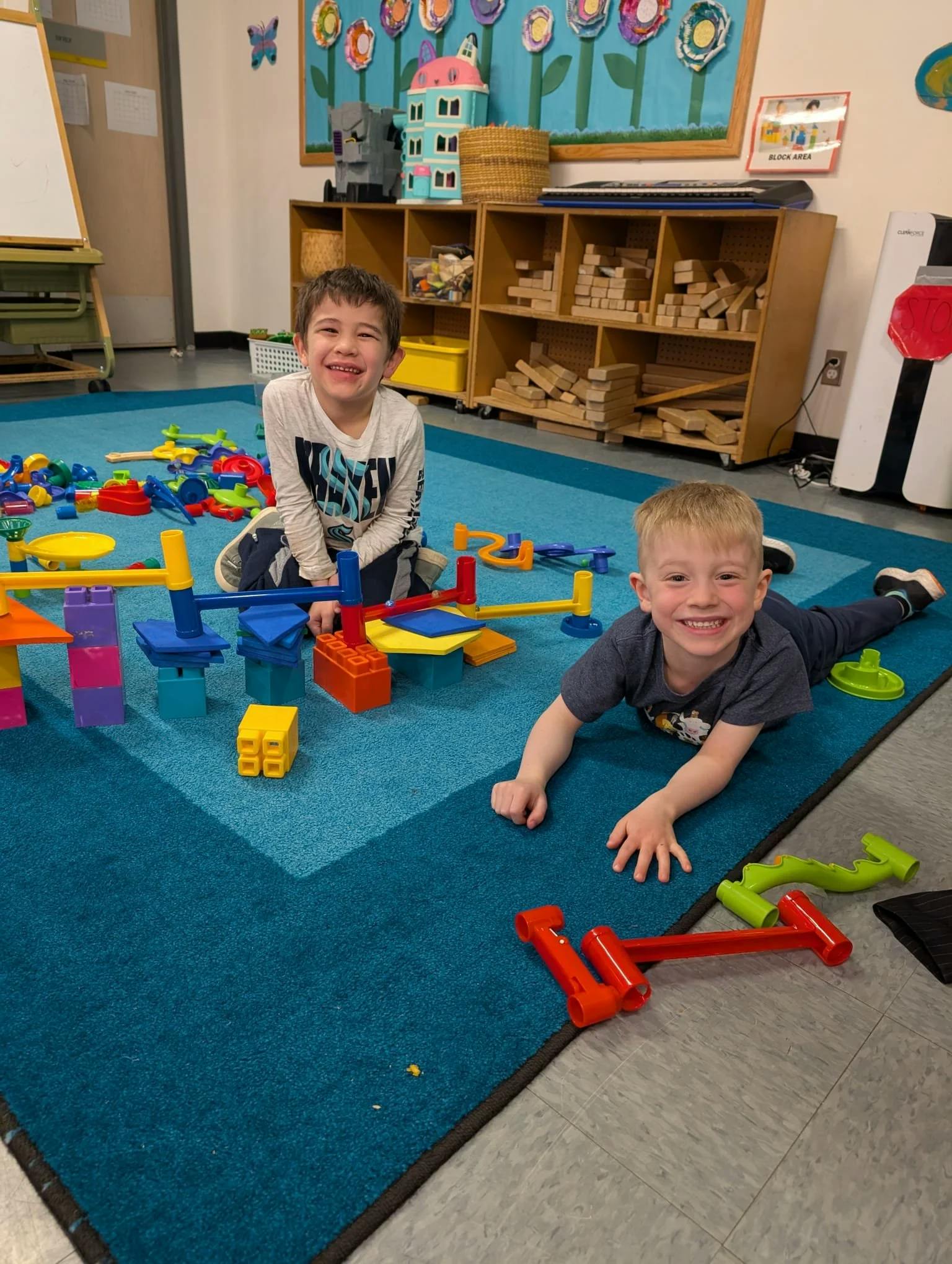 Two children playing with colorful building toys on a blue mat