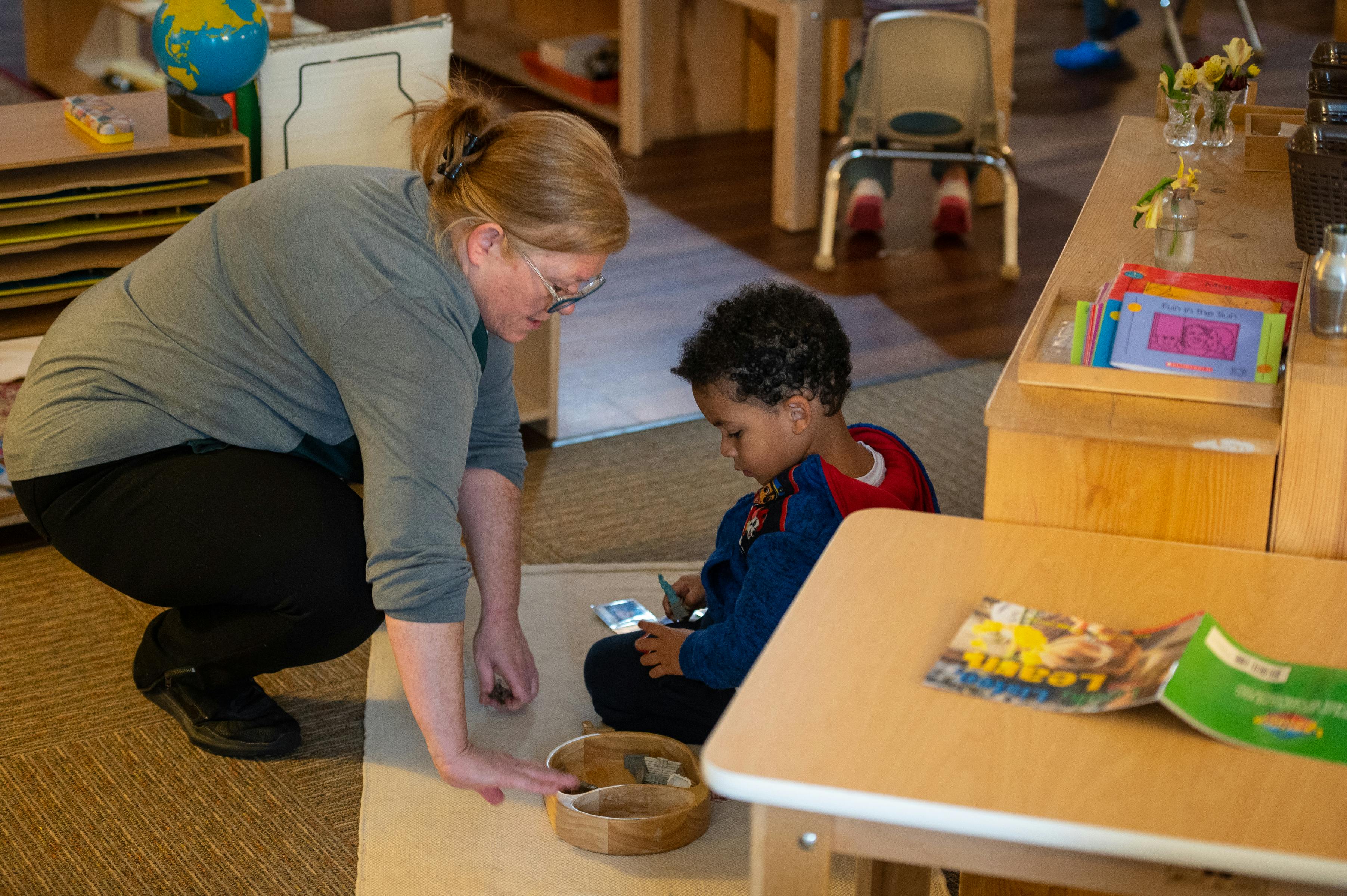 Adult person crouching next to a child sitting on the floor