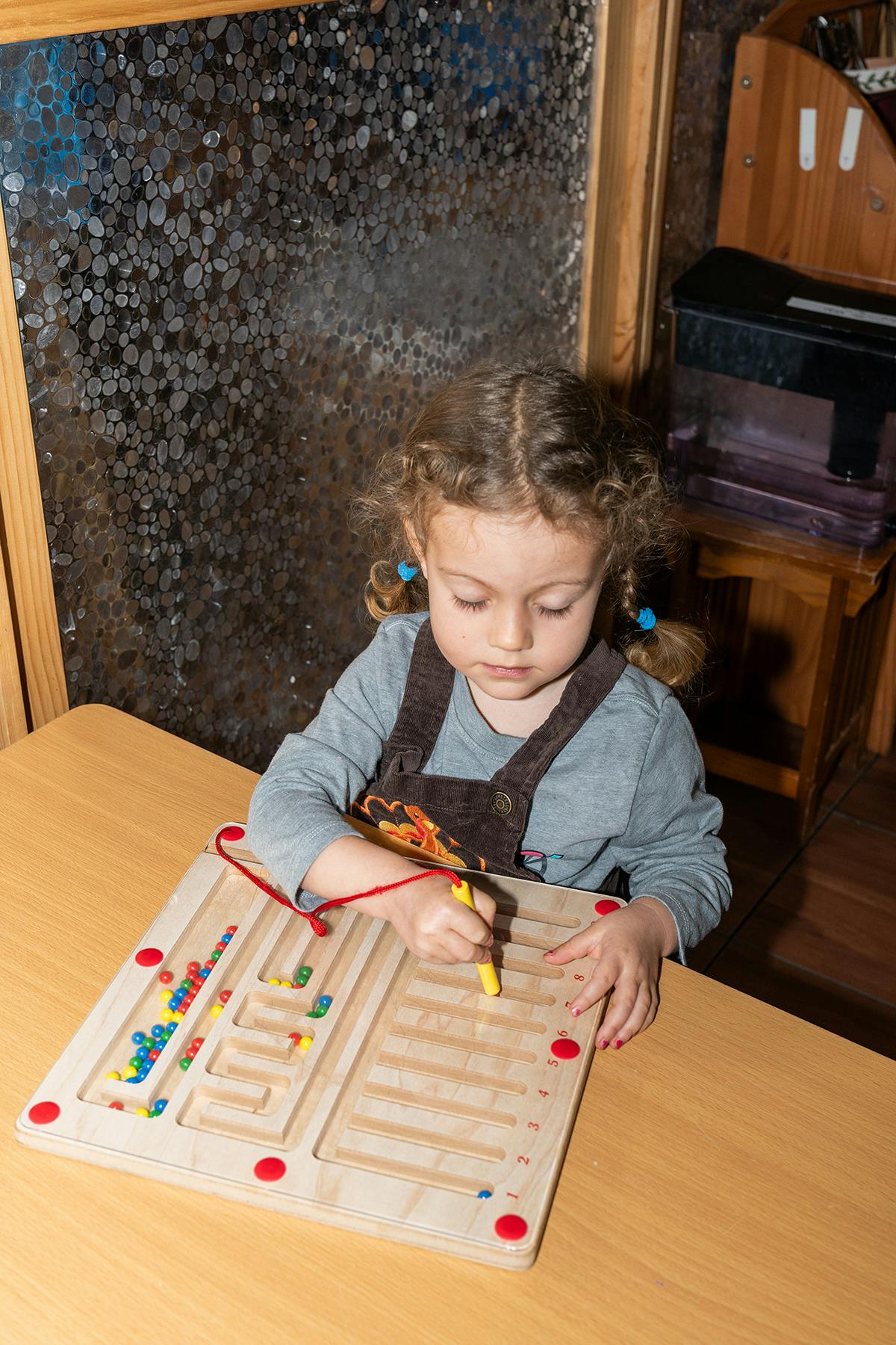 Child playing with a wooden maze board game on a table