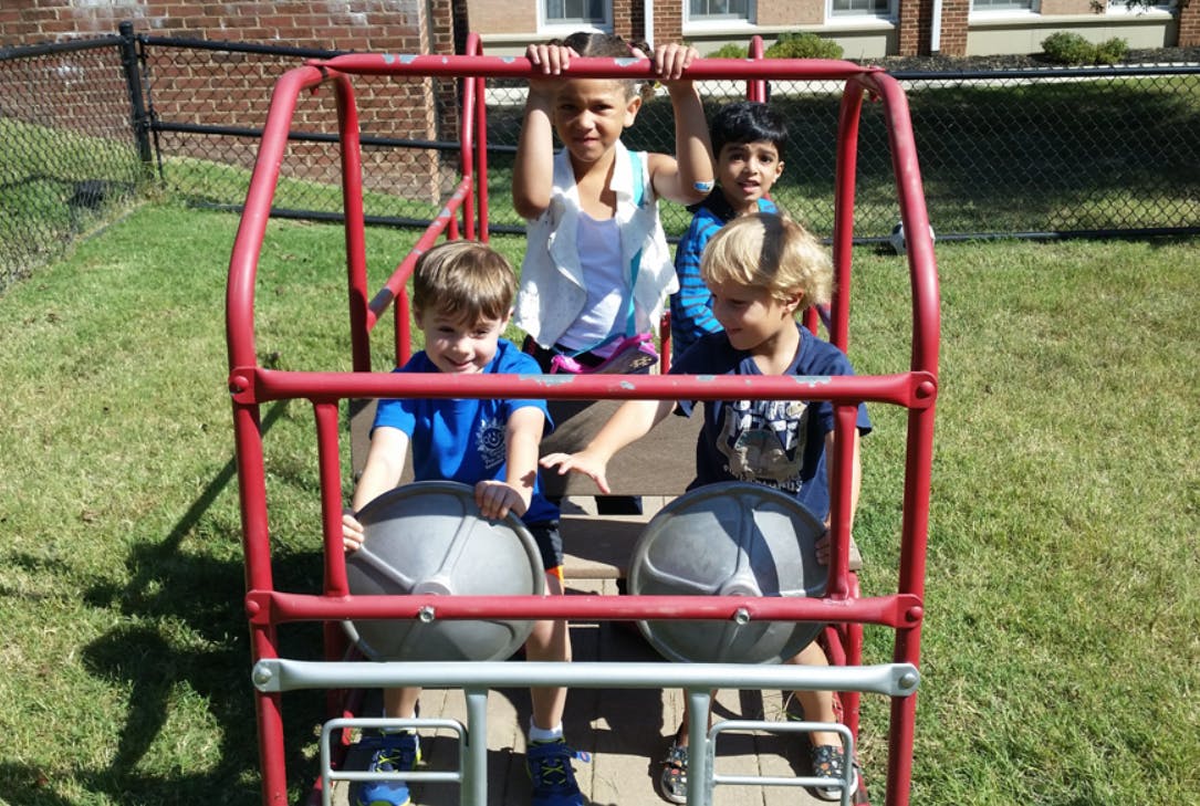 Four children playing on a red playground structure