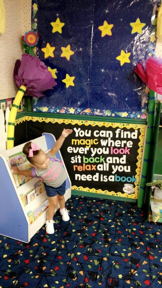 Child standing next to a book display with arms outstretched
