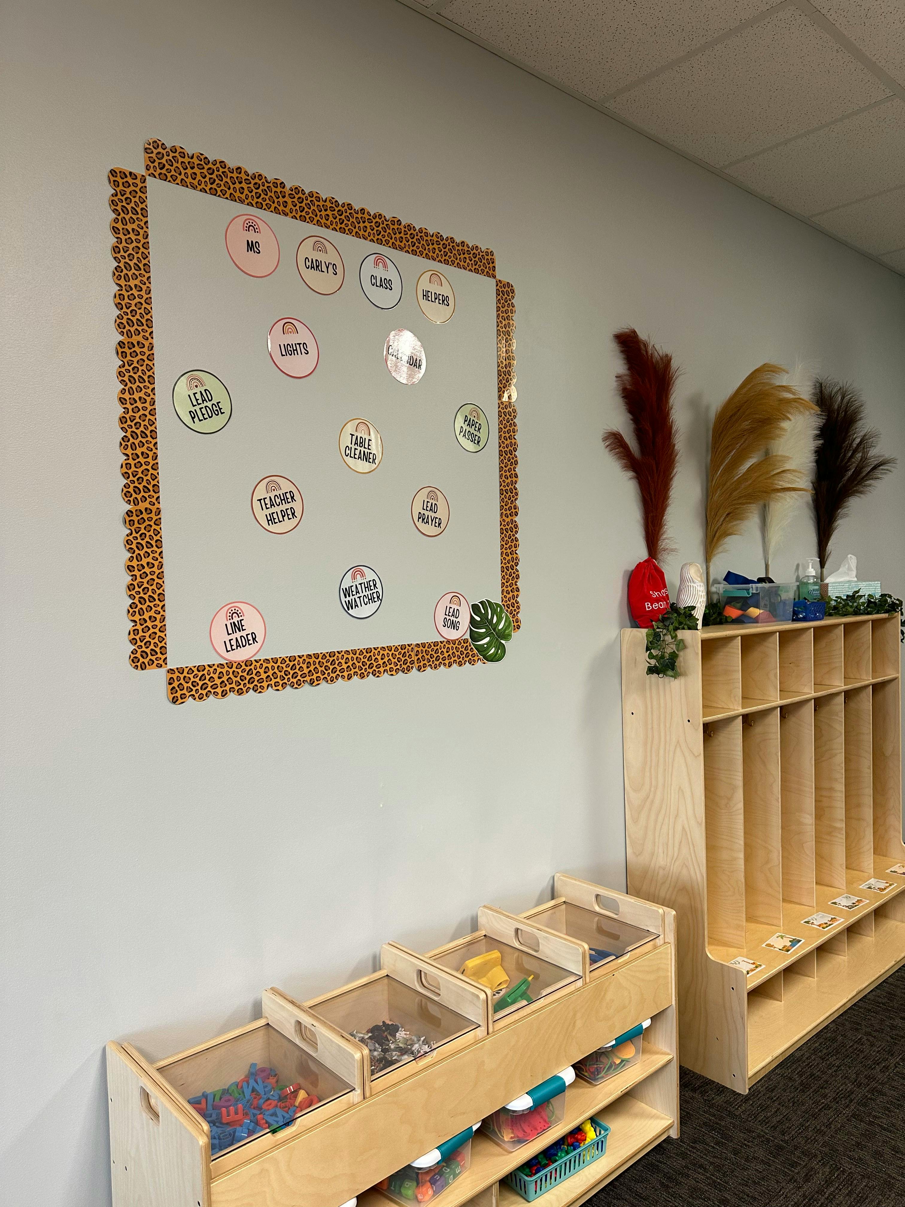 Bulletin board with round labels and wooden storage units in a classroom