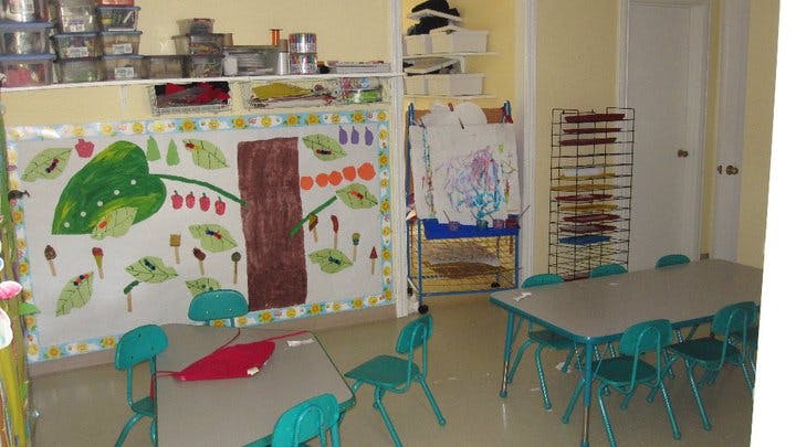 Classroom with tables, chairs, and children's artwork on the wall