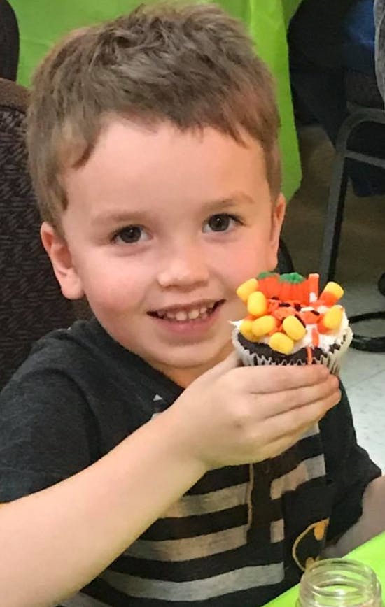 Child holding a cupcake decorated with candy corn