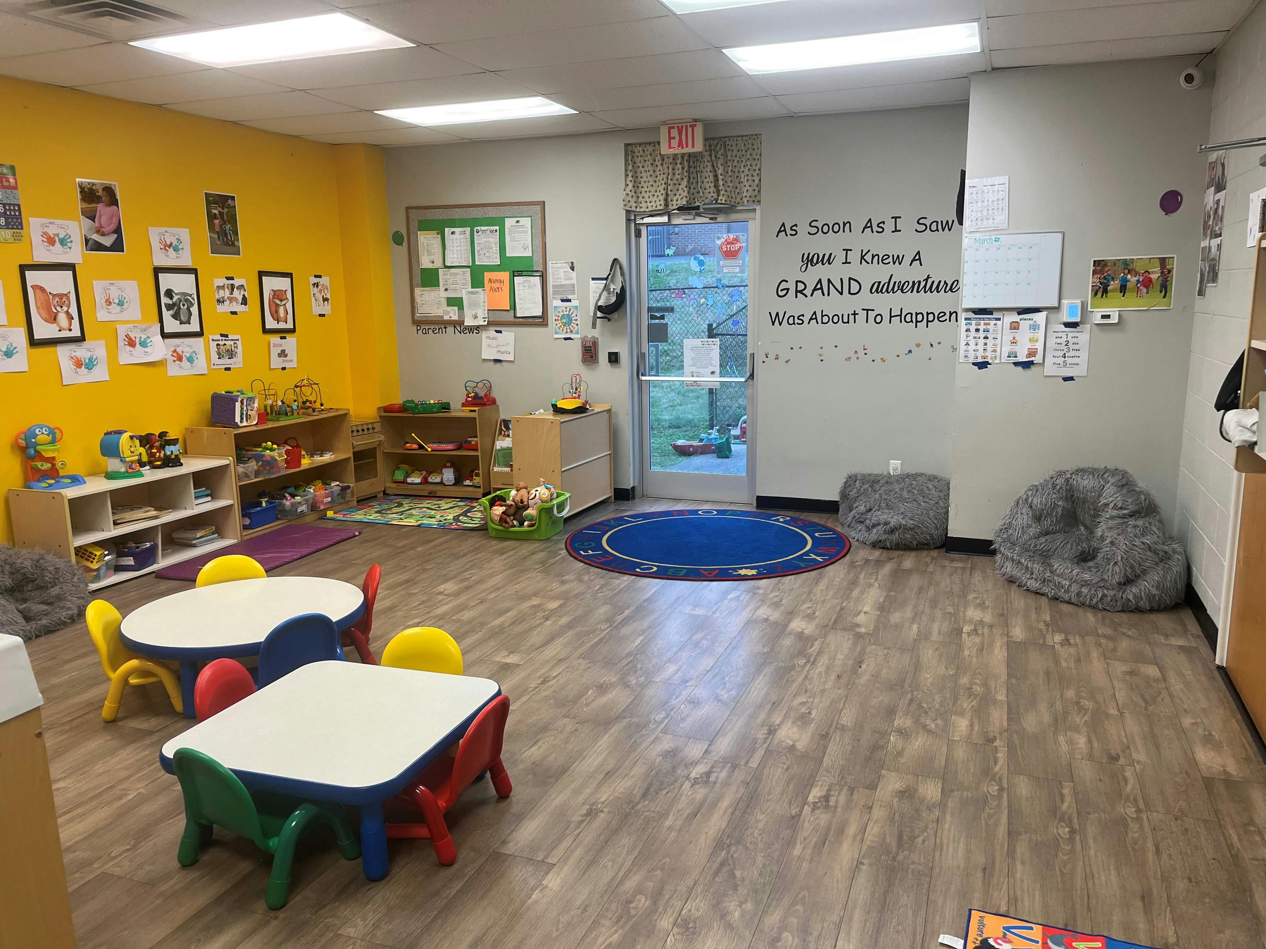 Classroom with small tables and chairs, toys on shelves, and wall decorations