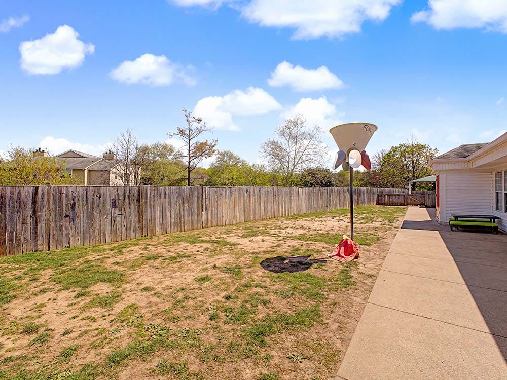 backyard with a wooden fence and a large, funnel-shaped game