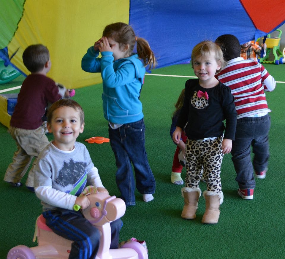 Children playing indoors, one child on a toy ride-on