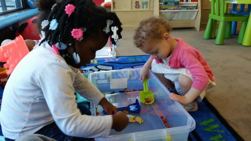 Two children playing with toys in a clear bin