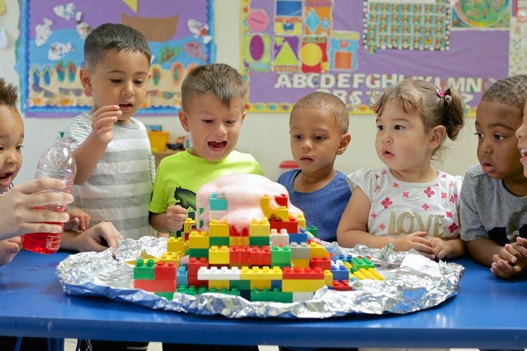 Children watching a volcano science experiment with building blocks