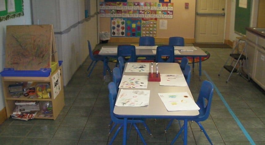 Classroom with small tables and chairs, artwork on walls