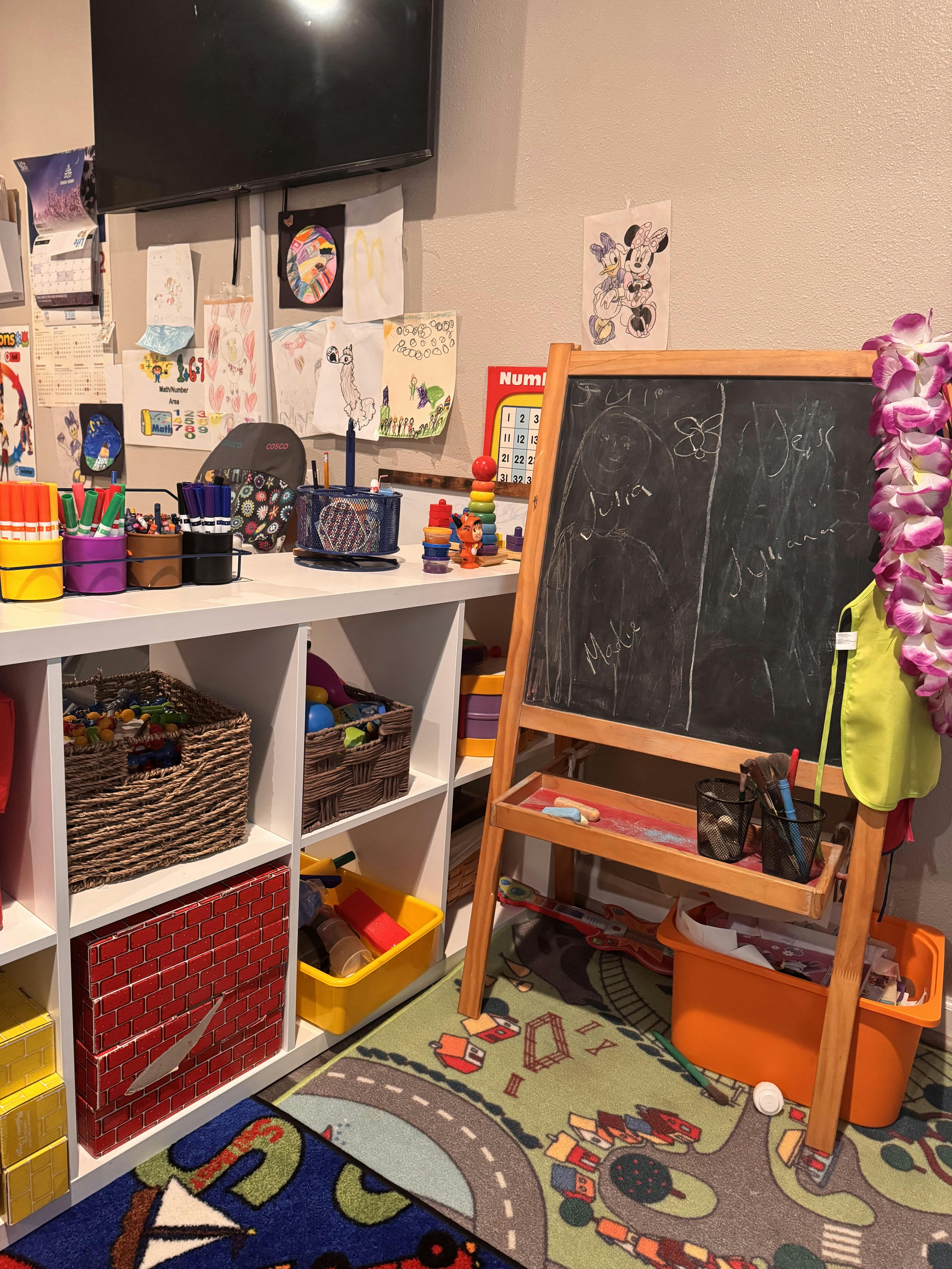 Child's playroom with an easel, storage shelves, and drawings on the wall