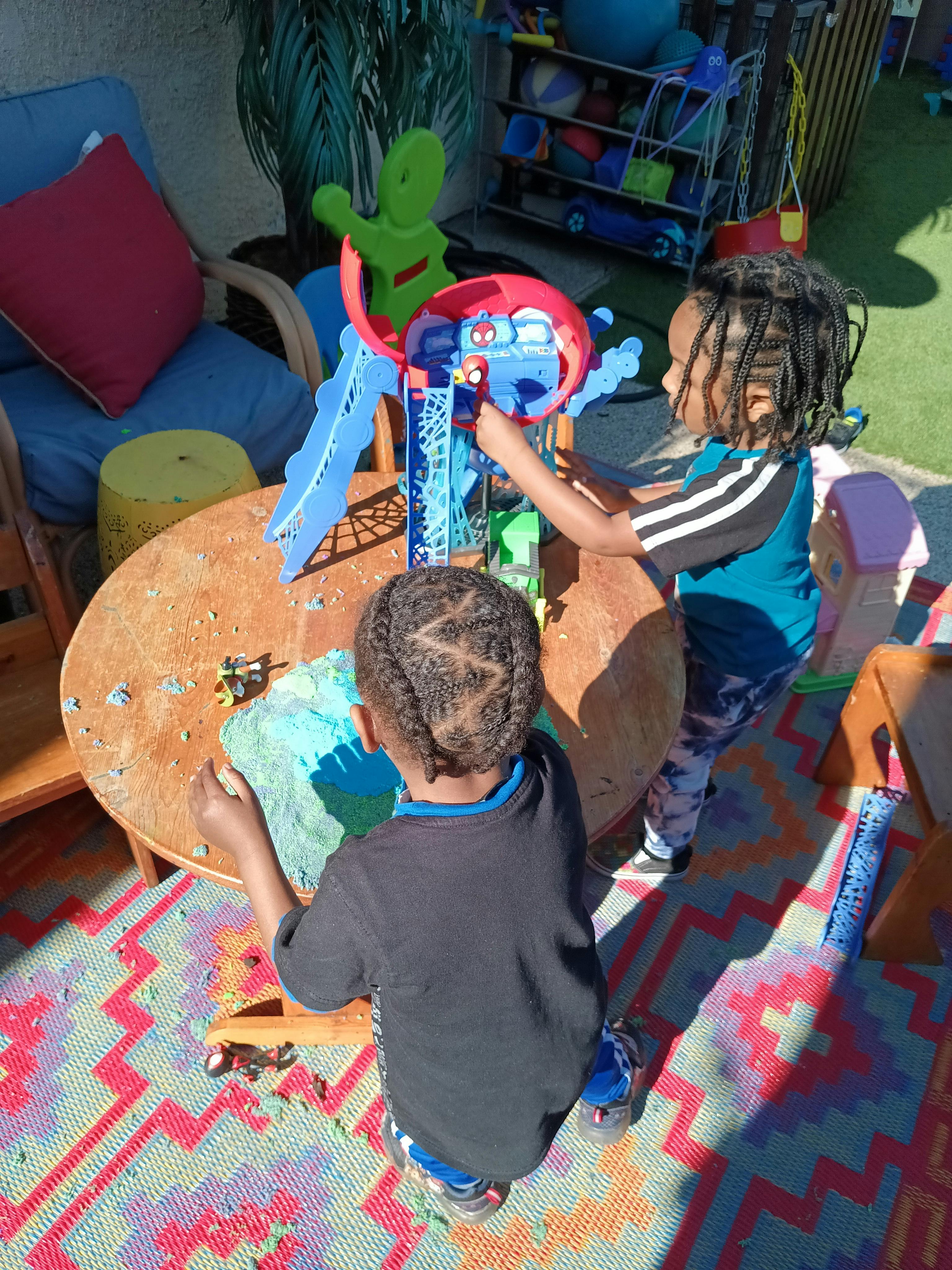 Two children playing with toys at a small table outdoors