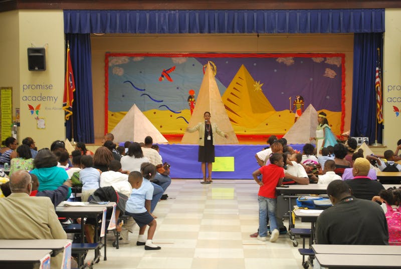 Person standing on stage in front of an audience in a school auditorium