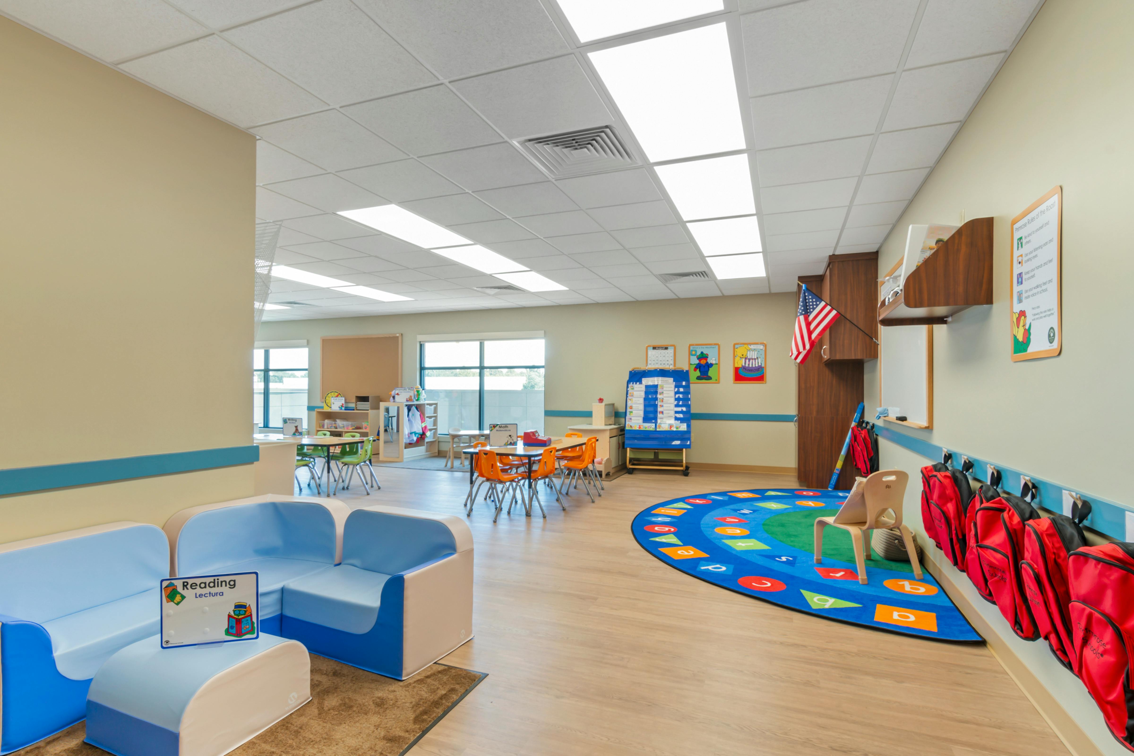 An empty early education classroom with small tables and chairs