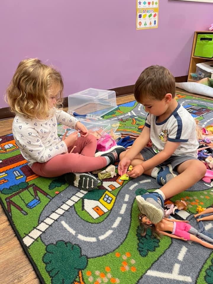 Two children playing with toys on a rug