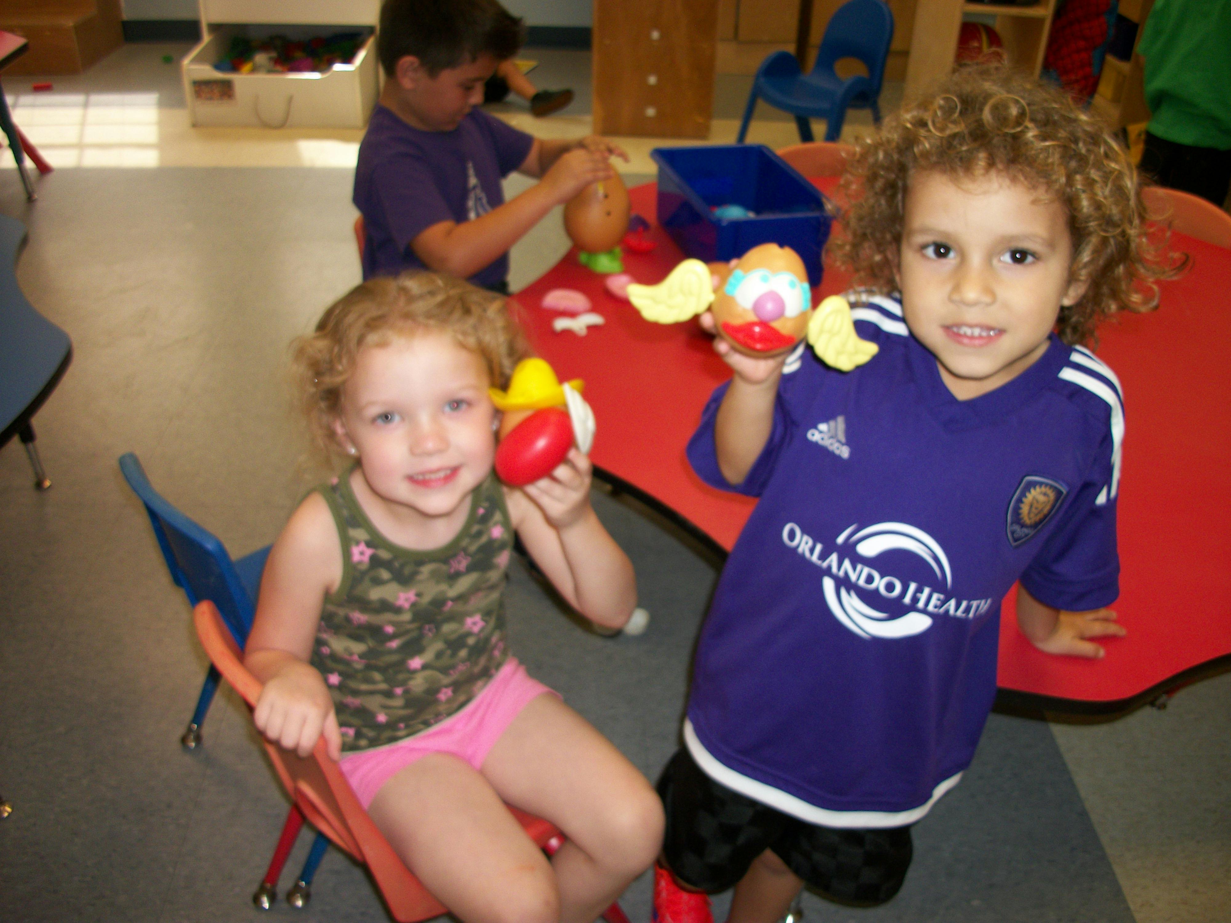 Two children holding toys in a classroom