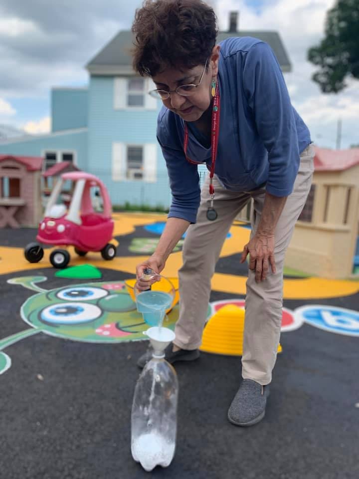 Person pouring liquid from a small cup into a funnel in a bottle