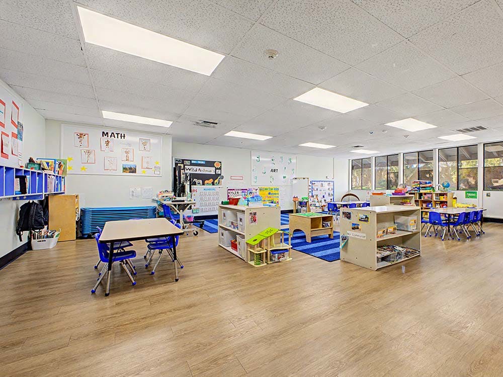 Empty classroom with tables, chairs, bookshelves, and large windows