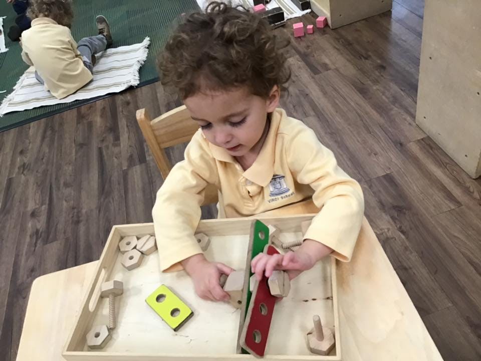 Child playing with wooden puzzle pieces at a table