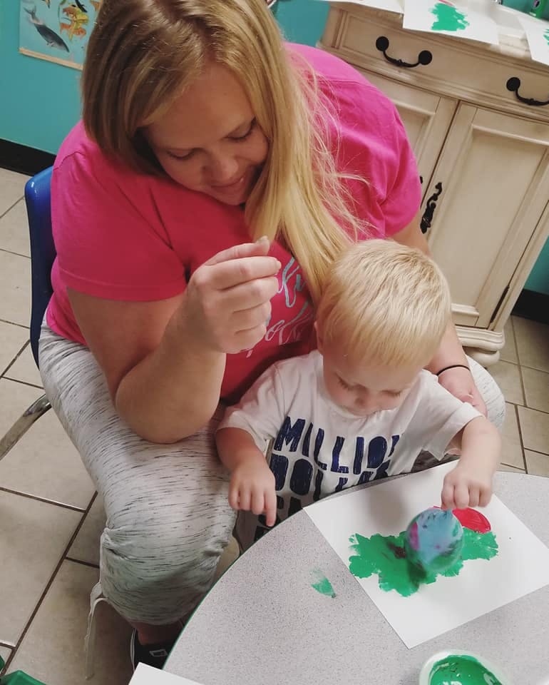 Person and child painting with green paint