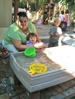 Adult and two children playing with water table