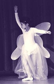 Child in a fairy costume with wings dancing