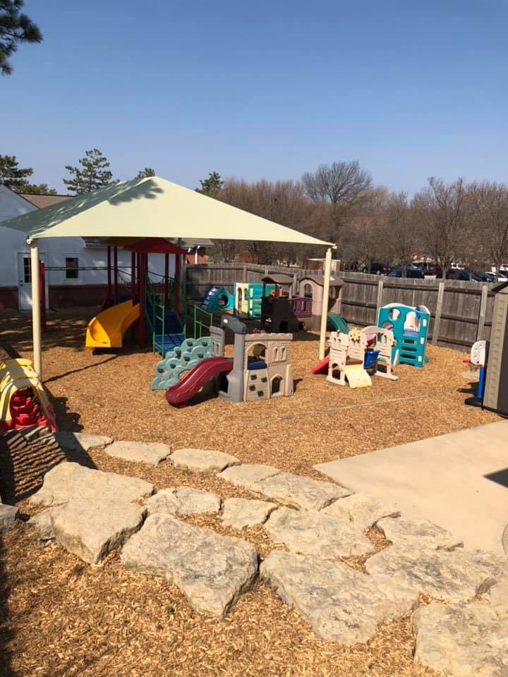 Outdoor playground with slides, play structures, and a large shade canopy