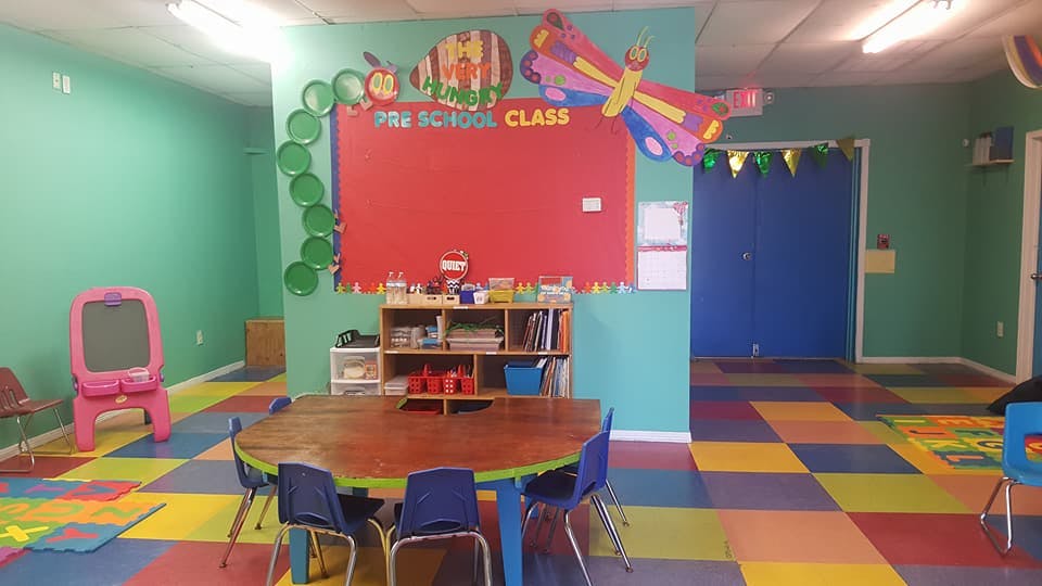Preschool classroom with colorful floor tiles and a red bulletin board