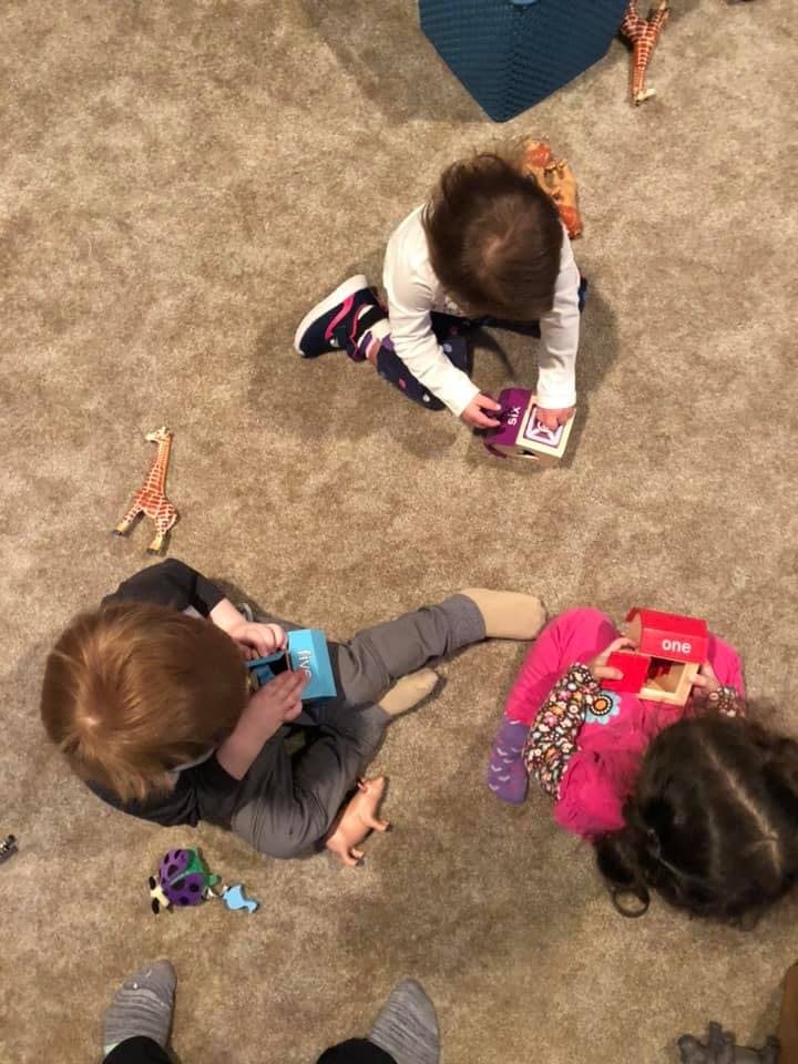 Two children playing with toys on a carpeted floor
