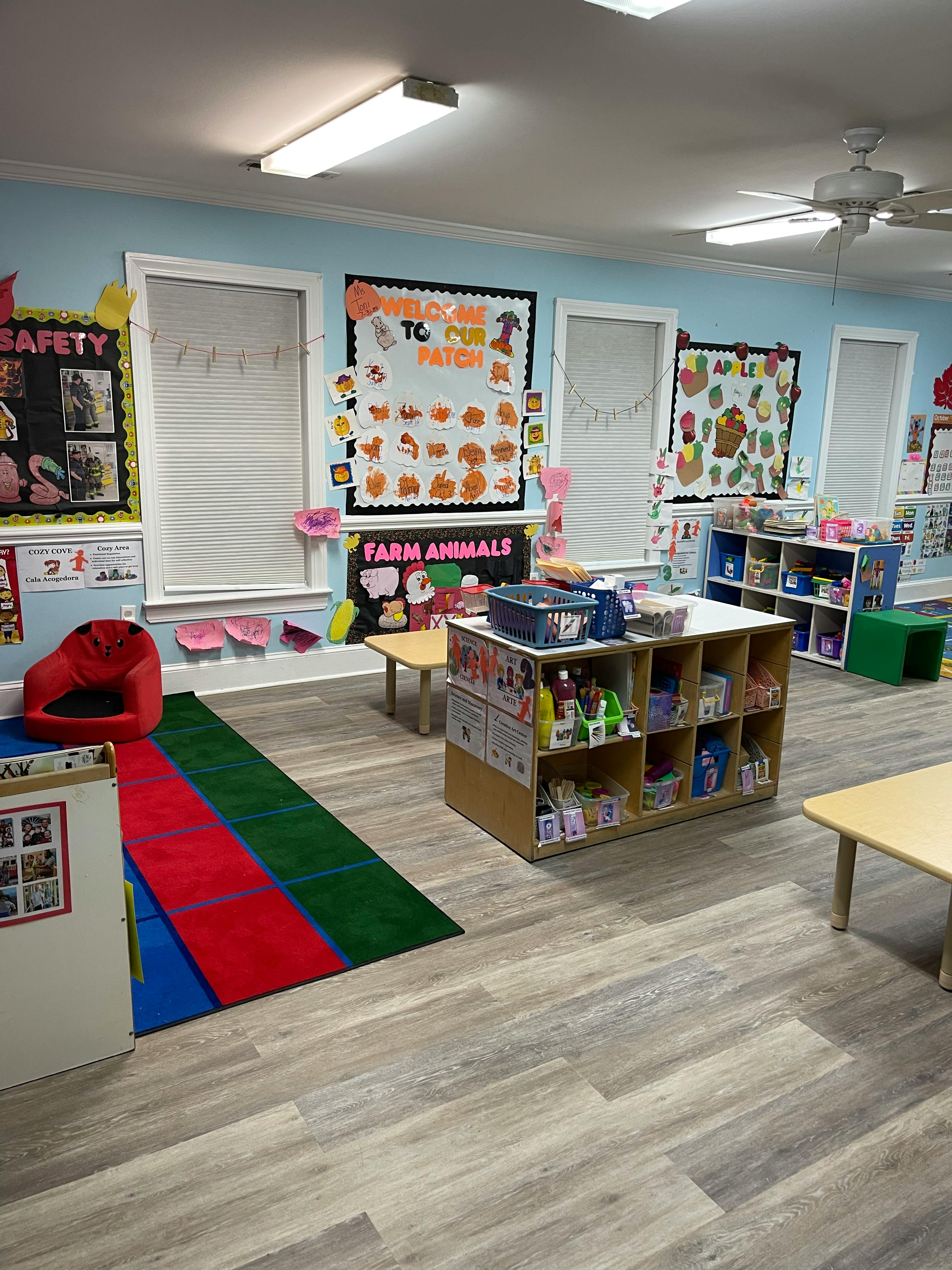 Empty classroom with colorful rugs, small tables, and educational posters