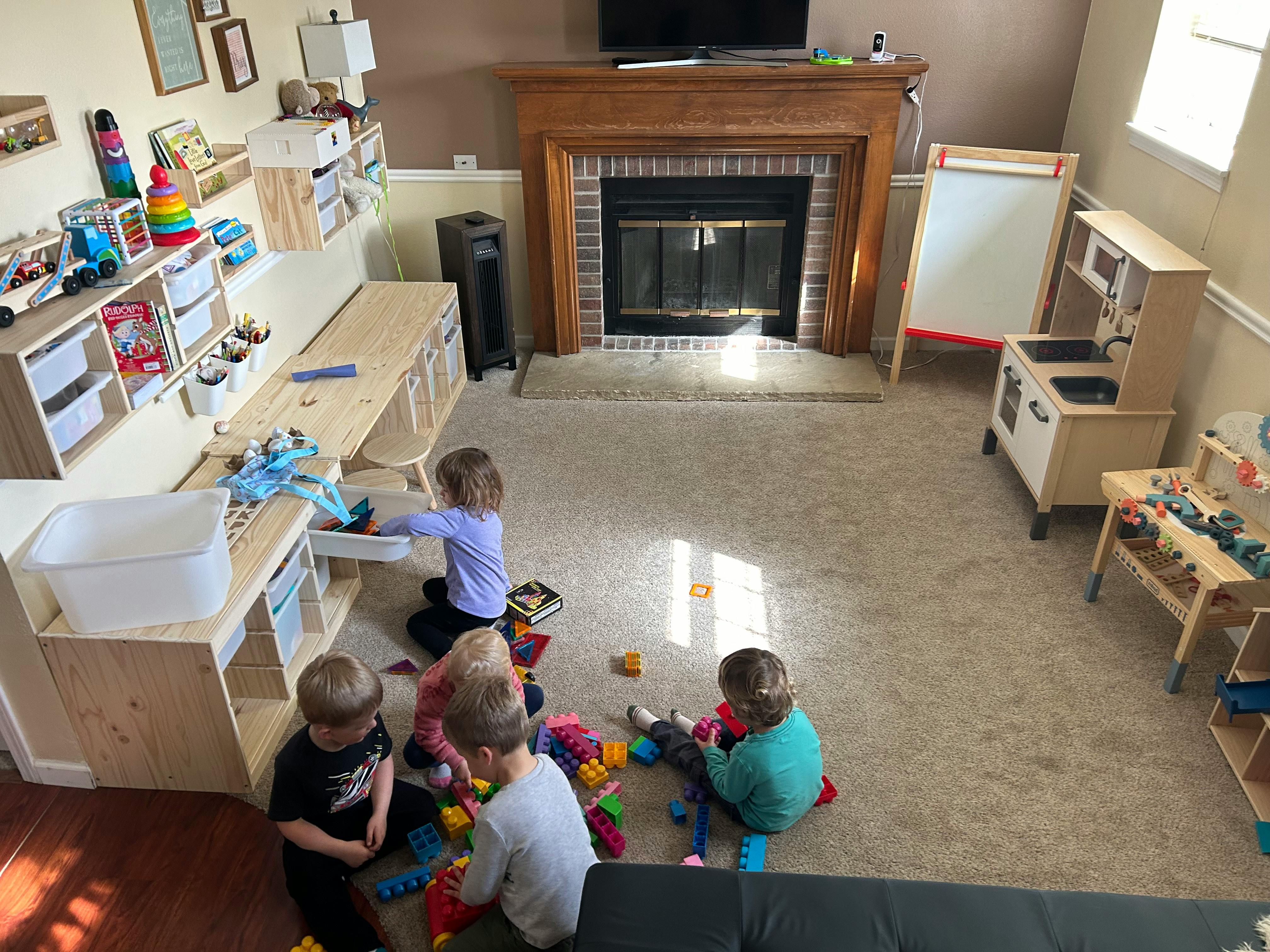 Children playing with toys in a room with a fireplace and play kitchen