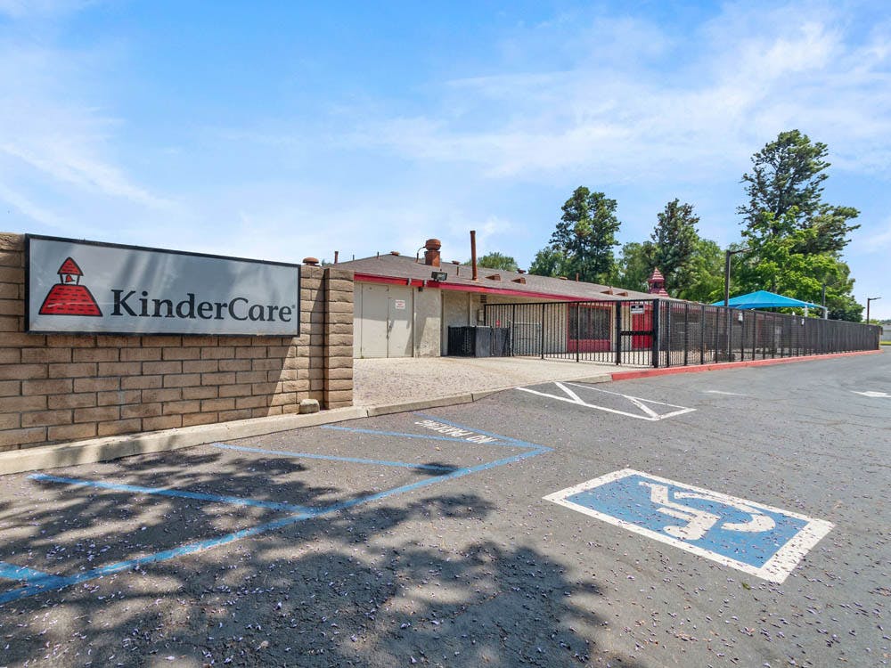 KinderCare sign on a brick wall next to a building and parking lot