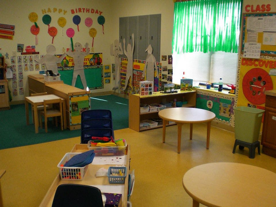 Empty classroom with small tables and chairs, colorful decorations on walls