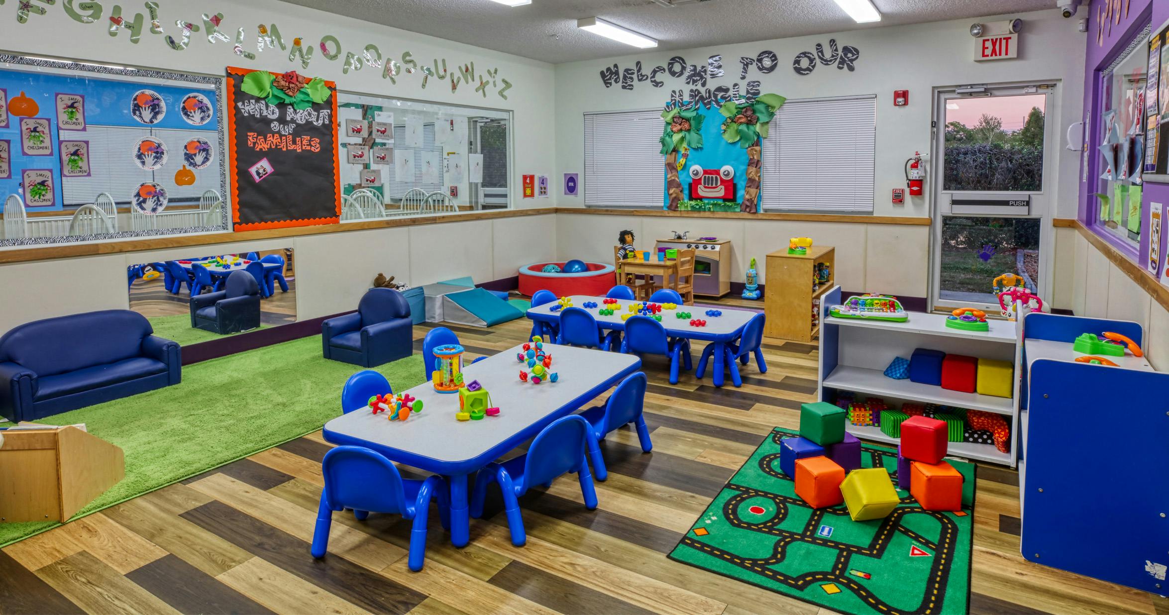 Colorful classroom with child-sized tables and chairs, play mats, and learning decorations