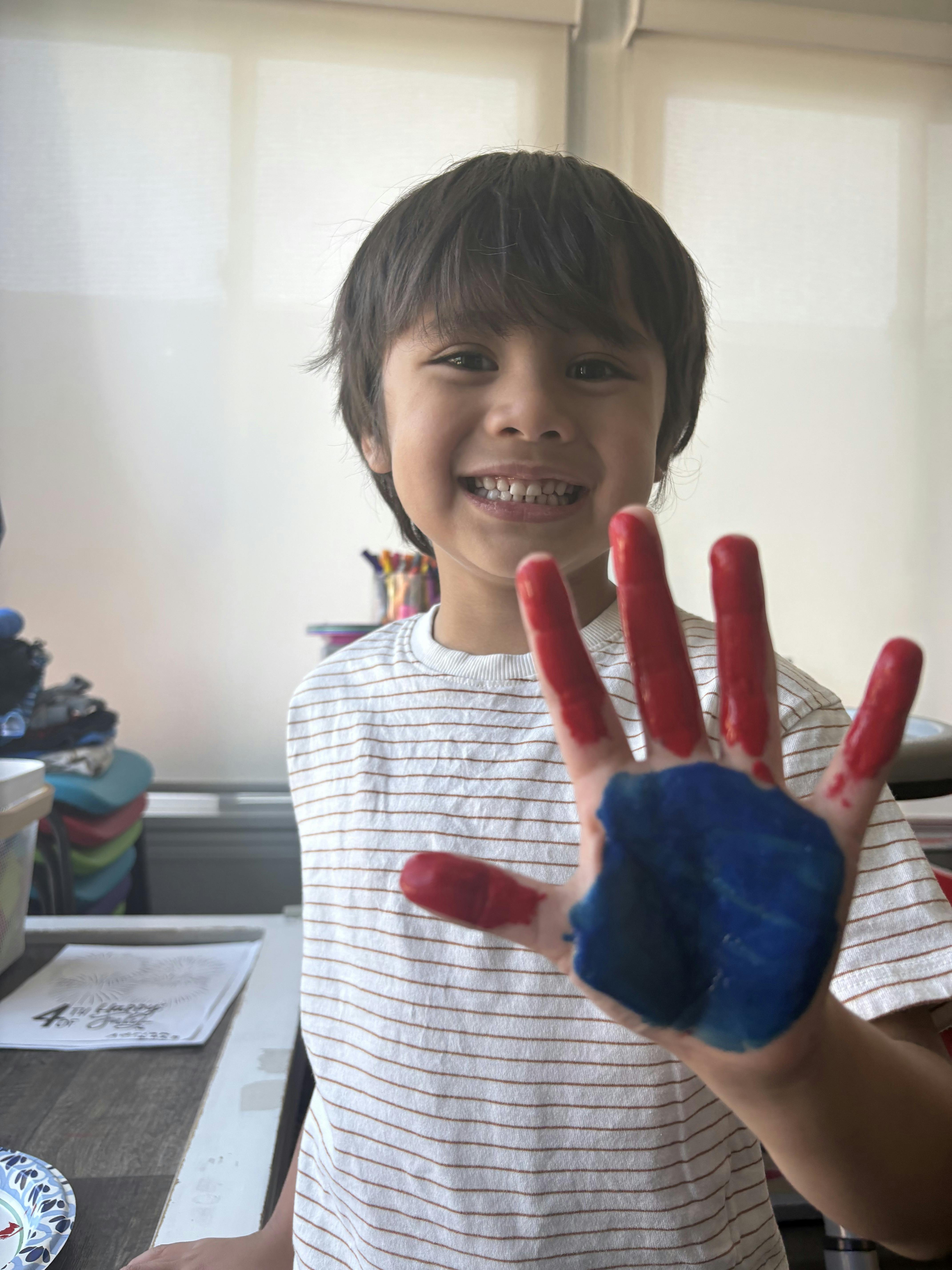 Child showing a hand covered in red and blue paint