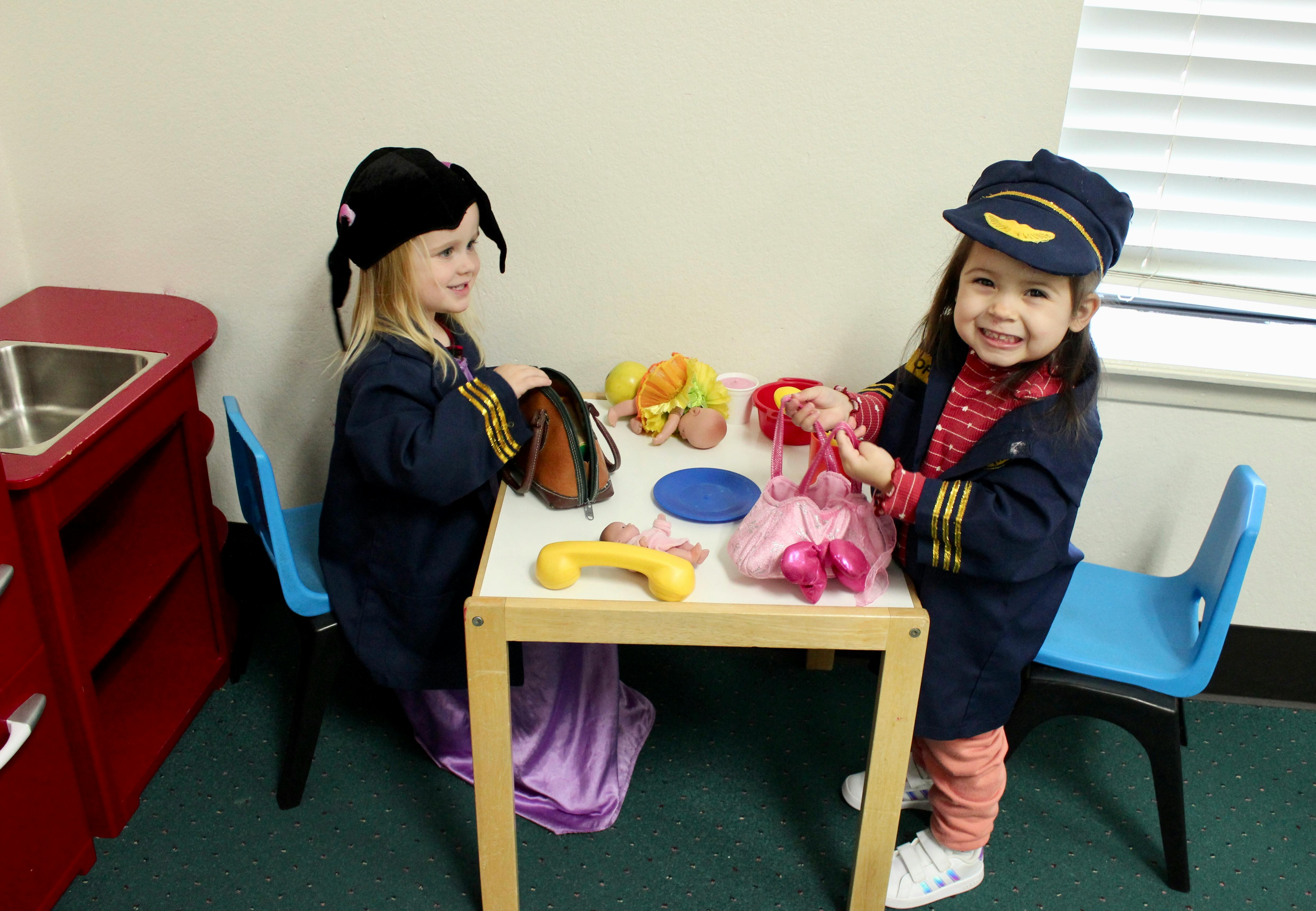 Two children playing with toys at a small table in a classroom