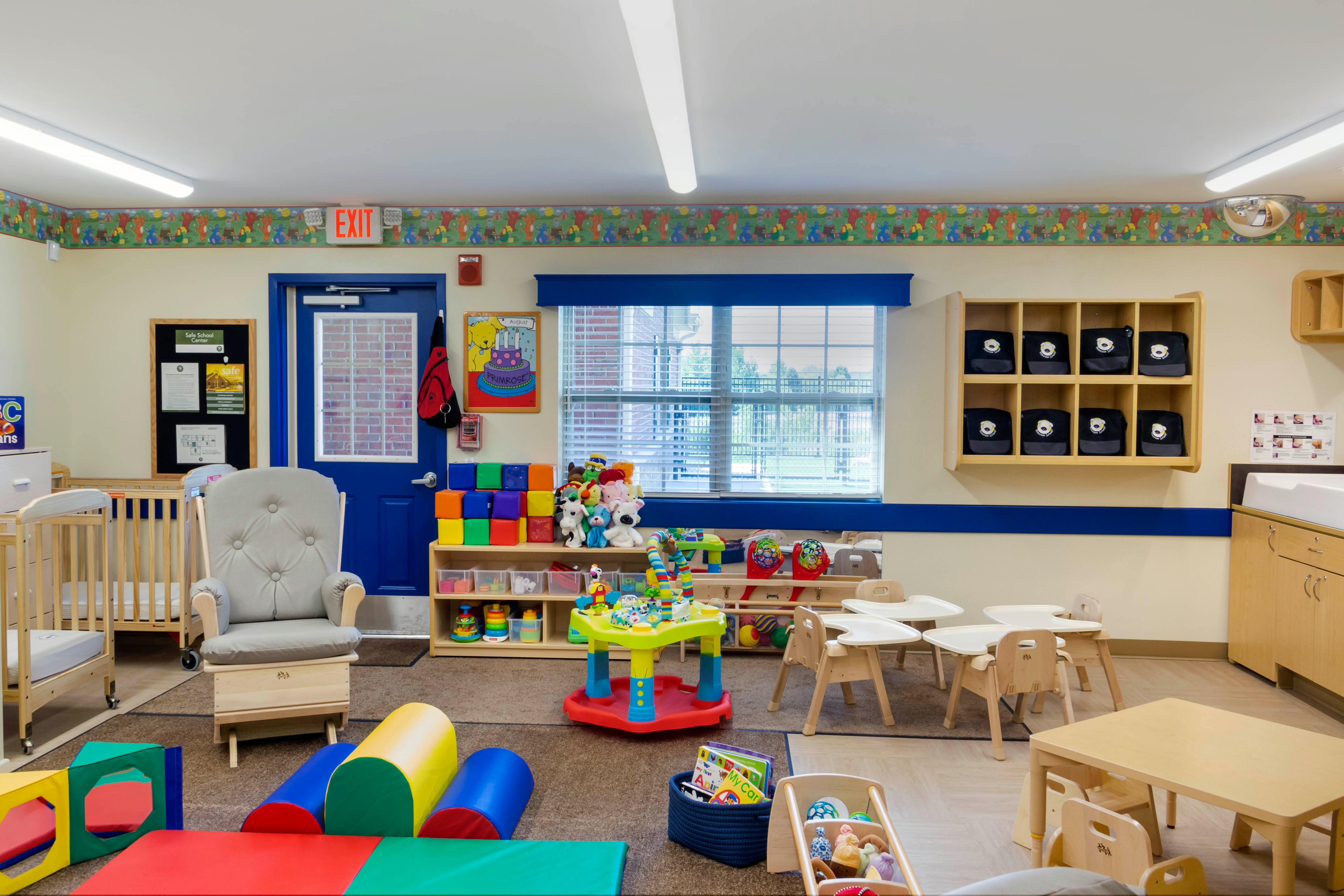 A colorful childcare classroom with various toys, cribs, and child-sized furniture