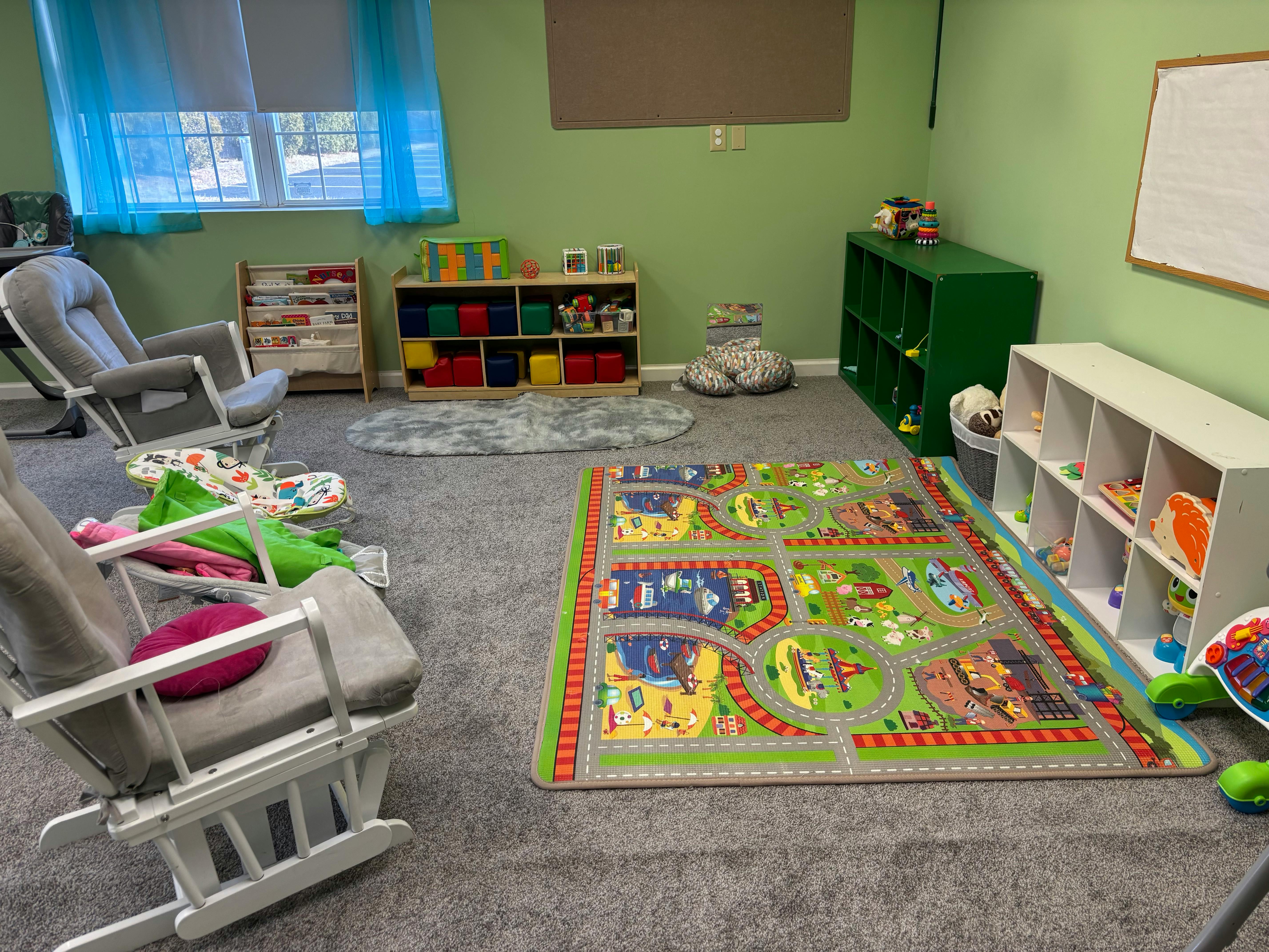 Playroom with two rocking chairs, toy storage, and a play mat
