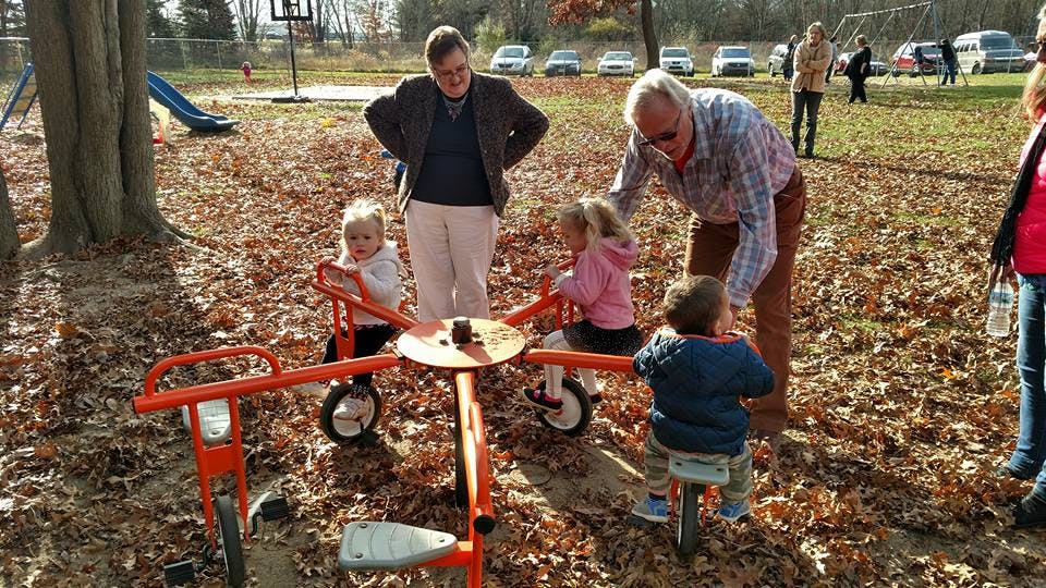 Adults with children on a playground merry-go-round