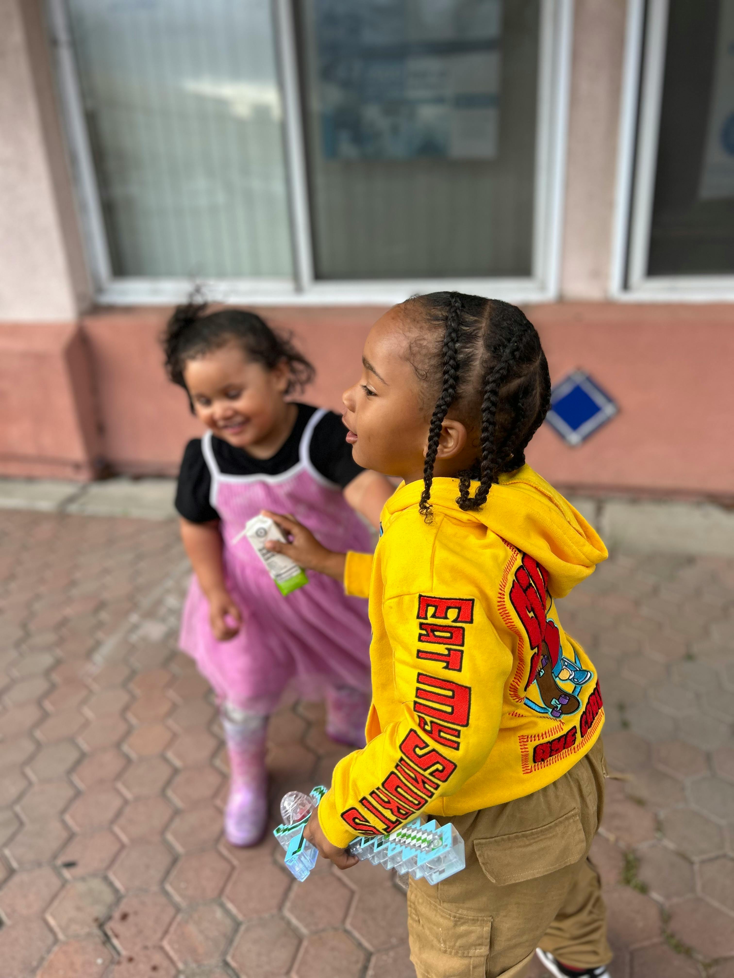 Two children playing outdoors, one holding a toy