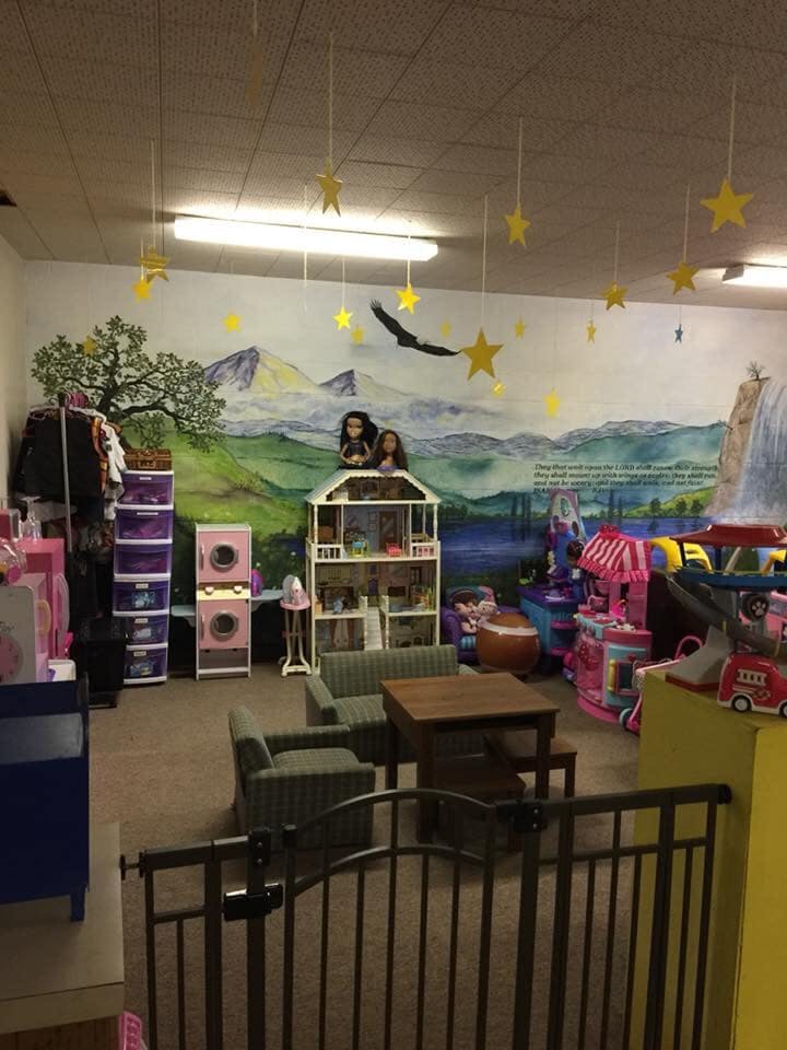 Playroom with dollhouse, toy kitchen, and mural of mountains and eagle